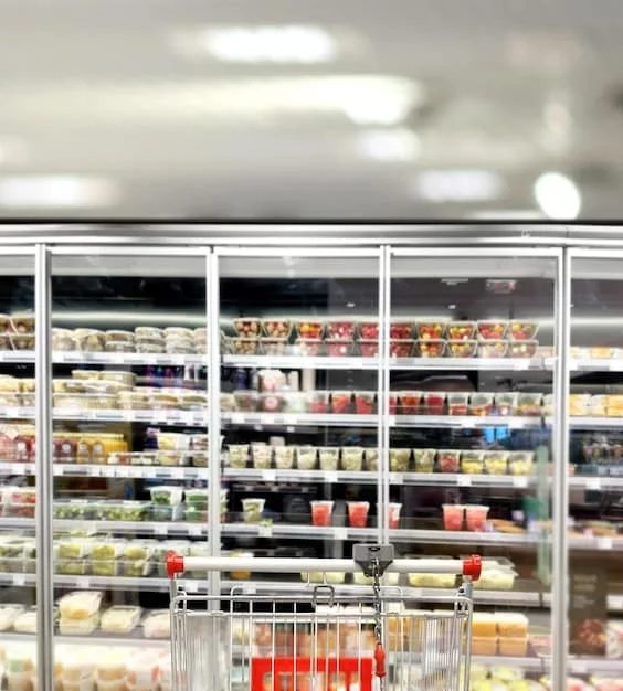 An interior shot of a Japanese convenience store, highlighting the refrigerated section with a wide variety of pre-made meals, sandwiches, and drinks. Focus on the abundance and visual appeal of the food offerings.