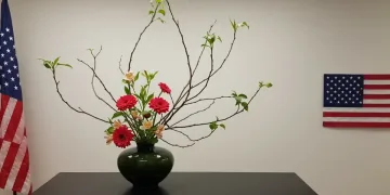 Serene Ikebana arrangement with vibrant flowers and branches in a minimalist setting, reflecting balance and harmony for US enthusiasts.