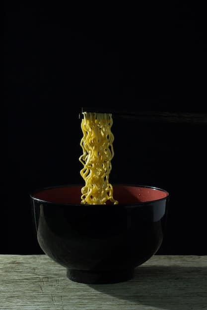 A close-up shot of a steaming bowl of ramen, with perfectly cooked noodles, a soft-boiled egg, slices of chashu pork, and nori seaweed. The broth is rich and flavorful, with visible droplets of oil shimmering on the surface.