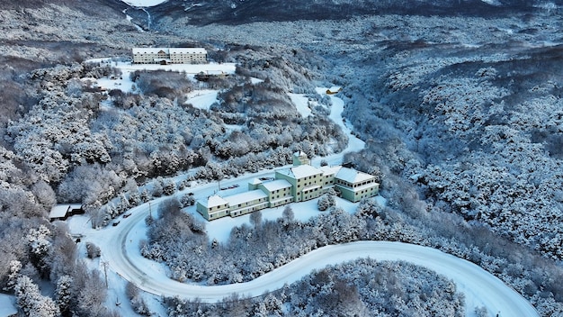An aerial view of a modern Japanese ski resort nestled in the mountains, featuring well-groomed slopes, chairlifts, and resort facilities. The image showcases the infrastructure and amenities available at a typical Japanese ski resort, surrounded by snow-covered forests and peaks.