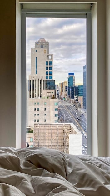 A modern hotel room in Japan with a comfortable bed, a desk, and a view of the city skyline.