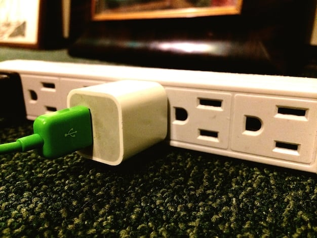 A close-up of a Japanese power outlet with a US adapter plugged into it. The adapter is clearly labeled, and the outlet looks modern and well-maintained. Focus on the visual representation of the voltage difference and the use of adapters.