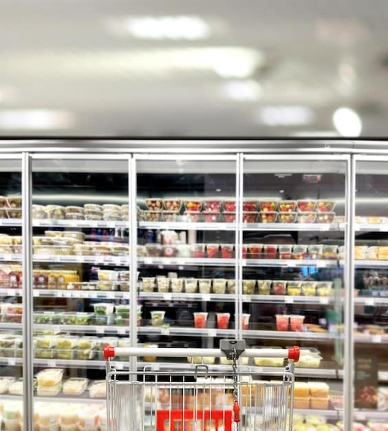 An interior shot of a Japanese convenience store, highlighting the refrigerated section with a wide variety of pre-made meals, sandwiches, and drinks. Focus on the abundance and visual appeal of the food offerings.
