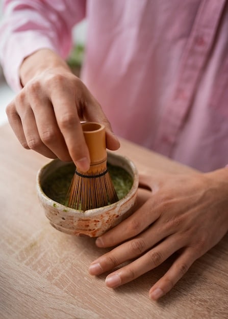 Close-up shot of hands gracefully performing the ritual of cleaning tea utensils during a Japanese tea ceremony. The hands are holding a chakin (linen cloth) and carefully wiping a chawan (tea bowl), with a focus on the precise and deliberate movements.