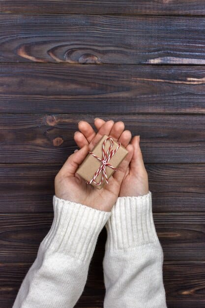 Close-up of hands exchanging a beautifully wrapped gift, highlighting the intricate wrapping and the respectful manner of giving and receiving.