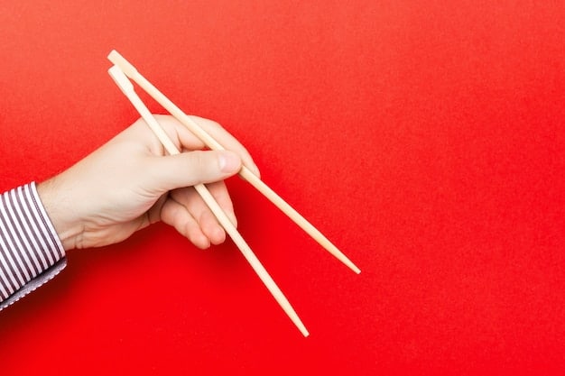 Close-up of hands demonstrating the correct way to hold chopsticks, with the chopstick rest visible in the background.