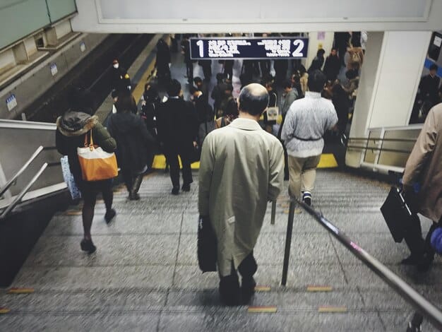 People queuing up neatly at a train station in Japan, waiting patiently behind the designated lines. Focus on capturing the sense of order and discipline.