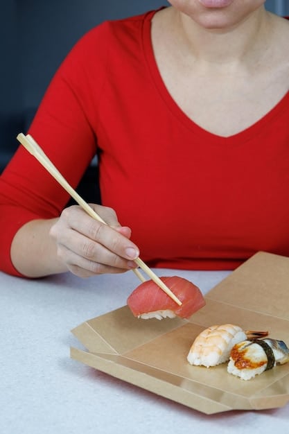 A close-up shot of a person skillfully using chopsticks to pick up sushi, demonstrating proper technique and grip. The focus is on the precision and elegance of the hand movements.