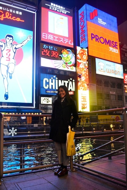 A US tourist proudly displaying a collection of various Japanese point cards in front of a neon-lit Tokyo street at night.