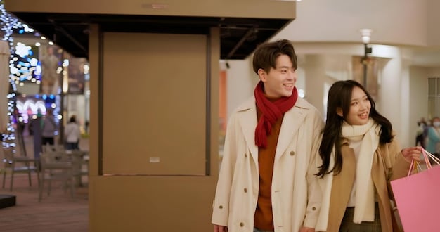 A US couple enthusiastically browsing racks of high-end designer clothes at a well-lit, spacious Japanese outlet mall, with price tags clearly visible and smiling faces.